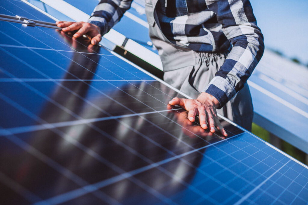 A technician carefully inspects the surface of a solar panel during installation for cheaper electricity.